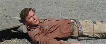 Movie still from “Flaming Star” (1960), directed by Don Siegel – A man laying on the ground in a field; Medium shot, High angle