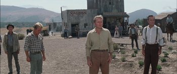Movie still from “Flaming Star” (1960), directed by Don Siegel – A man standing in front of an old western saloon; Wide shot, Low angle