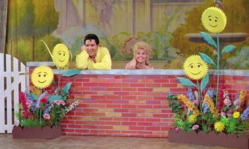 Movie still from “Frankie and Johnny” (1966), directed by Frederick De Cordova – A couple of people sitting on a brick wall with smiley faces; Wide shot, Low angle