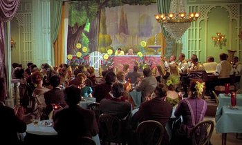 Movie still from “Frankie and Johnny” (1966), directed by Frederick De Cordova – A crowd of people sitting at tables in front of a stage; Wide shot, Over the shoulder angle