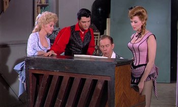 Movie still from “Frankie and Johnny” (1966), directed by Frederick De Cordova – A group of people sitting around a wooden table; Medium shot, Low angle