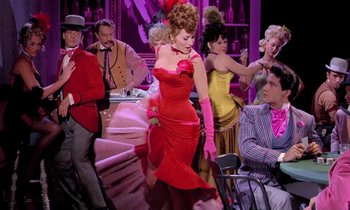 Movie still from “Frankie and Johnny” (1966), directed by Frederick De Cordova – A woman in a red dress is dancing in front of a group of men; Wide shot, Low angle