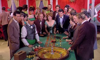 Movie still from “Frankie and Johnny” (1966), directed by Frederick De Cordova – A group of people gathered around a roulette table; Wide shot, High angle