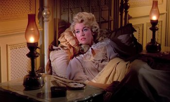 Movie still from “Frankie and Johnny” (1966), directed by Frederick De Cordova – A woman sitting on a couch in a living room; Medium shot, High angle