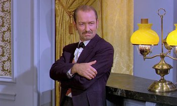 Movie still from “Frankie and Johnny” (1966), directed by Frederick De Cordova – A man in a suit and tie standing with his arms crossed; Medium shot, Low angle