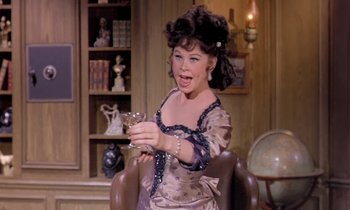 Movie still from “Frankie and Johnny” (1966), directed by Frederick De Cordova – A woman in a dress is holding a glass in her hand; Medium shot, Over the shoulder angle