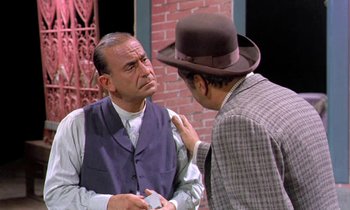 Movie still from “Frankie and Johnny” (1966), directed by Frederick De Cordova – A man in a suit and a man in a hat talking to each other; Medium shot, Over the shoulder angle