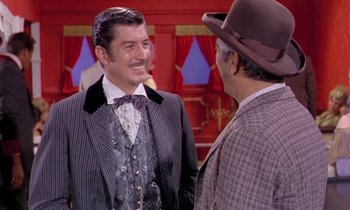 Movie still from “Frankie and Johnny” (1966), directed by Frederick De Cordova – A man in a suit and tie talking to another man in a hat; Medium shot, Over the shoulder angle