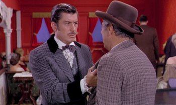 Movie still from “Frankie and Johnny” (1966), directed by Frederick De Cordova – A man in a suit and a hat talking to another man in a suit; Medium shot, Over the shoulder angle