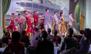 Movie still from “Frankie and Johnny” (1966), directed by Frederick De Cordova – A group of people are standing in front of a stage; Wide shot, High angle