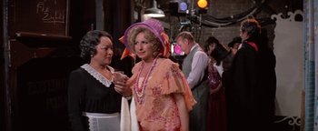 Movie still from “Funny Lady” (1975), directed by Herbert Ross – A woman in an orange dress and a purple hat; Medium shot, Over the shoulder angle