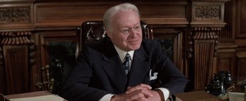 Movie still from “Funny Lady” (1975), directed by Herbert Ross – An older man sitting in a chair wearing a suit and tie; Close Up shot, High angle