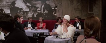Movie still from “Funny Lady” (1975), directed by Herbert Ross – A group of people sitting at a table in a restaurant; Wide shot, Over the shoulder angle