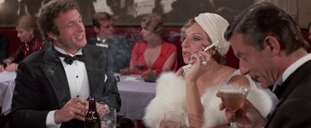 Movie still from “Funny Lady” (1975), directed by Herbert Ross – A woman talking on a cell phone in front of other people; Close Up shot, Over the shoulder angle