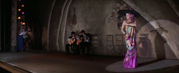 Movie still from “Funny Lady” (1975), directed by Herbert Ross – A group of men and women playing instruments in front of a woman; Wide shot, Low angle