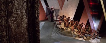 Movie still from “Funny Lady” (1975), directed by Herbert Ross – A group of people sitting on a stage with a woman dressed as a vampire; Extreme Wide shot, High angle