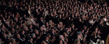 Movie still from “Funny Lady” (1975), directed by Herbert Ross – A large group of people in black tuxedos clapping; Extreme Wide shot, High angle