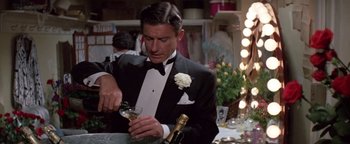 Movie still from “Funny Lady” (1975), directed by Herbert Ross – A man in a tuxedo holding a glass of champagne; Medium shot, High angle