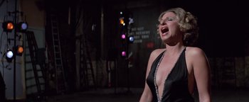 Movie still from “Funny Lady” (1975), directed by Herbert Ross – A woman in a black dress singing in a dark room; Medium shot, Low angle