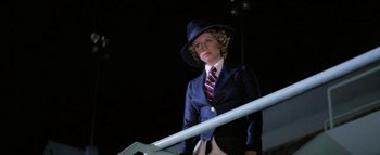 Movie still from “Funny Lady” (1975), directed by Herbert Ross – A woman in a suit and hat standing on a stair railing at night; Medium shot, Low angle