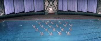 Movie still from “Funny Lady” (1975), directed by Herbert Ross – A large group of people swimming in a swimming pool; Extreme Wide shot, High angle