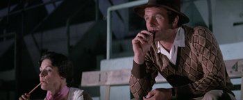 Movie still from “Funny Lady” (1975), directed by Herbert Ross – A man in a brown hat is smoking a cigarette; Medium shot, Over the shoulder angle