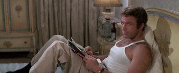 Movie still from “Funny Lady” (1975), directed by Herbert Ross – A man sitting on the floor reading a magazine; Medium shot, High angle