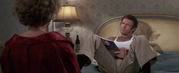 Movie still from “Funny Lady” (1975), directed by Herbert Ross – A man sitting on a bed reading a magazine; Medium shot, Over the shoulder angle