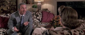 Movie still from “Funny Lady” (1975), directed by Herbert Ross – A man sitting on a couch in front of a woman; Medium shot, Over the shoulder angle