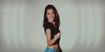 Movie still from “Gianluca Vacchi - Mucho Más” (2022), directed by Tommaso Deboni – A woman in a black shirt and blue jean shorts; Medium shot, High angle