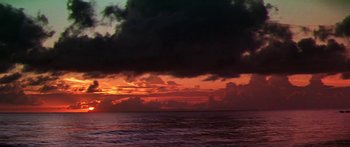 Movie still from “Hawaii” (1966), directed by George Roy Hill – The sun is setting over the ocean with dark clouds in the background; Extreme Wide shot, Low angle