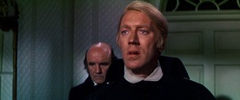 Movie still from “Hawaii” (1966), directed by George Roy Hill – A man with a bald head in a room with another man in the background; Close Up shot, Over the shoulder angle