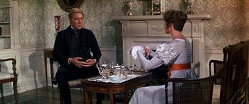 Movie still from “Hawaii” (1966), directed by George Roy Hill – Two people sitting at a table in front of a fireplace; Medium shot, Over the shoulder angle