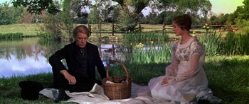 Movie still from “Hawaii” (1966), directed by George Roy Hill – Two people sitting on a blanket near a body of water; Medium shot, High angle