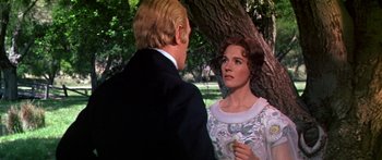 Movie still from “Hawaii” (1966), directed by George Roy Hill – A man and a woman standing next to a tree; Medium shot, Over the shoulder angle