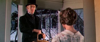 Movie still from “Hawaii” (1966), directed by George Roy Hill – A man in a top hat and a woman in a floral dress; Medium shot, Low angle