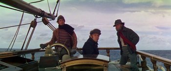 Movie still from “Hawaii” (1966), directed by George Roy Hill – A group of men sitting on a boat in the water; Medium shot, Low angle