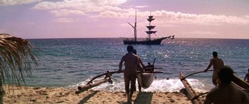 Movie still from “Hawaii” (1966), directed by George Roy Hill – A man walking on the beach with a boat in the background; Extreme Wide shot, High angle