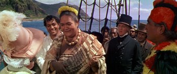 Movie still from “Hawaii” (1966), directed by George Roy Hill – A woman in traditional dress on a boat with other people; Medium shot, Over the shoulder angle