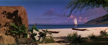 Movie still from “Hawaii” (1966), directed by George Roy Hill – A beach with a boat in the background and a tree in the foreground; Extreme Wide shot, High angle