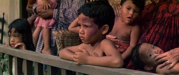 Movie still from “Hawaii” (1966), directed by George Roy Hill – A young boy sitting on top of a wooden bench; Medium shot, High angle