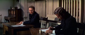 Movie still from “Hawaii” (1966), directed by George Roy Hill – Two men sitting at a table writing on papers; Medium shot, Over the shoulder angle