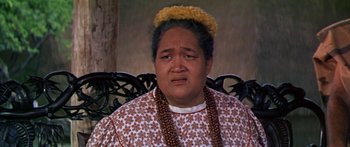 Movie still from “Hawaii” (1966), directed by George Roy Hill – An older woman wearing a necklace and a flower crown; Close Up shot, Over the shoulder angle