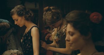 Movie still from “House of Tolerance” (2011), directed by Bertrand Bonello – A woman is looking at a necklace on her neck; Medium shot, Over the shoulder angle