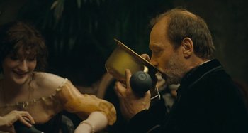 Movie still from “House of Tolerance” (2011), directed by Bertrand Bonello – A man is drinking from a cup while sitting on a chair; Close Up shot, Over the shoulder angle