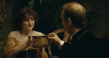 Movie still from “House of Tolerance” (2011), directed by Bertrand Bonello – A man and a woman are holding a cup; Medium shot, Over the shoulder angle