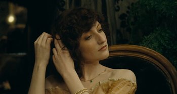 Movie still from “House of Tolerance” (2011), directed by Bertrand Bonello – A beautiful woman with curly brown hair wearing a yellow dress; Close Up shot, High angle