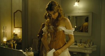Movie still from “House of Tolerance” (2011), directed by Bertrand Bonello – A woman in a corset looking down at a piece of paper; Medium shot, Over the shoulder angle