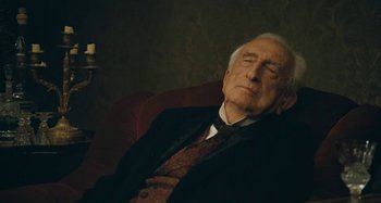 Movie still from “House of Tolerance” (2011), directed by Bertrand Bonello – An older man is sleeping on a chair; Close Up shot, High angle