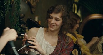 Movie still from “House of Tolerance” (2011), directed by Bertrand Bonello – A young woman sitting at a table looking at her cell phone; Close Up shot, Over the shoulder angle